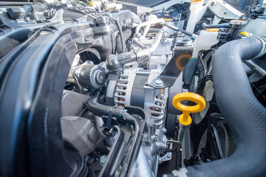 close up of a car engine bay showing an alternator and dipstick